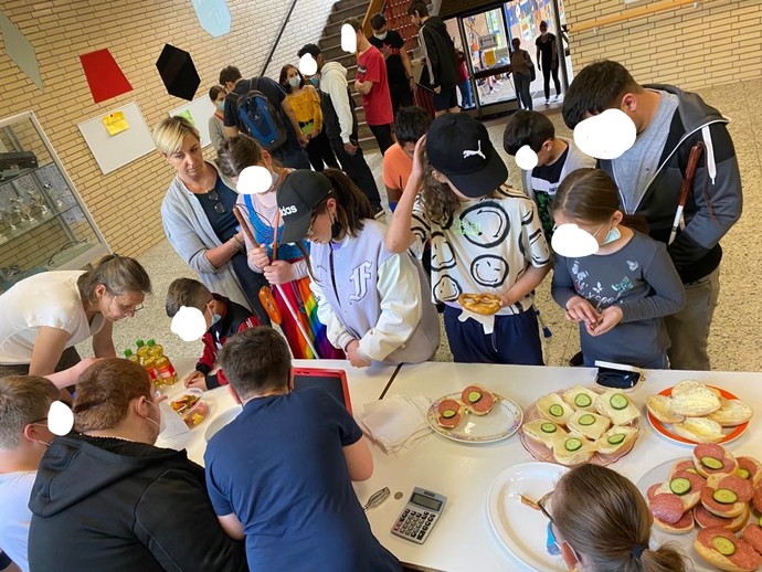 Schülerinnen und Schüler kaufen am Kiosk Brötchen und Süßigkeiten ein.