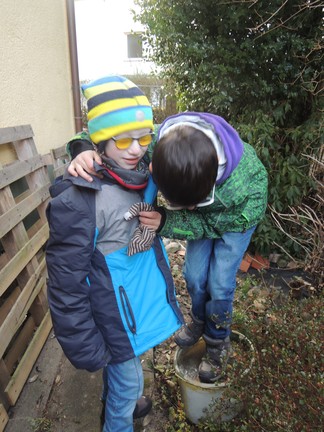Schüler stehen auf einem Eimer mit gefrorenem Wasser