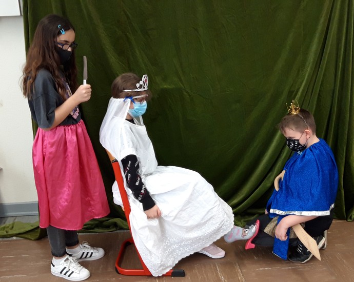 Zwei Mädchen und ein Junge mit Verkleidung spielen das Märchen Aschenputtel.