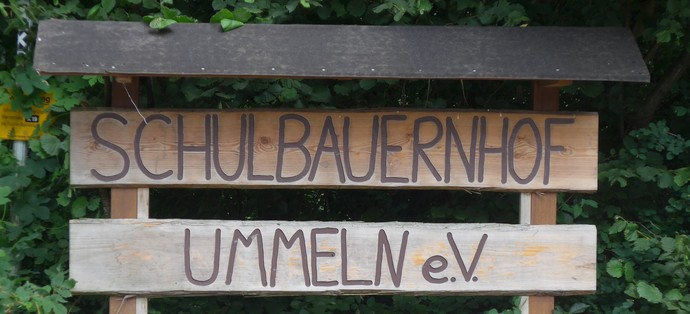 Ein Holzschild mit der Aufschrift "Schulbauernhof Ummeln"