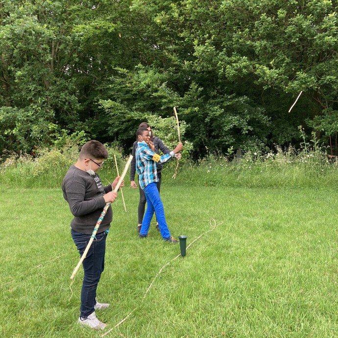 Einige Jugendliche stehen auf einer Wiese und üben Bogenschießen. (vergrößerte Bildansicht wird geöffnet)