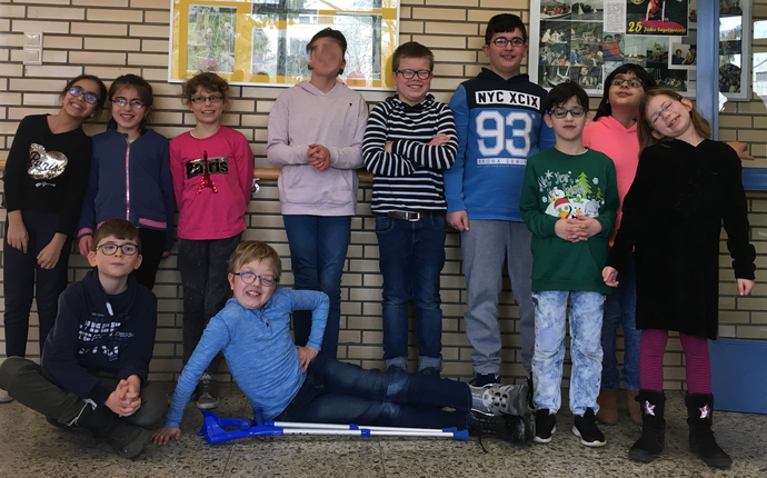 Die Gewinner des Vorlesewettbewerbs: Sieben Kinder stehen stolz im Foyer der Opticus Schule. Ein Kind sitzt vorne auf dem Boden.