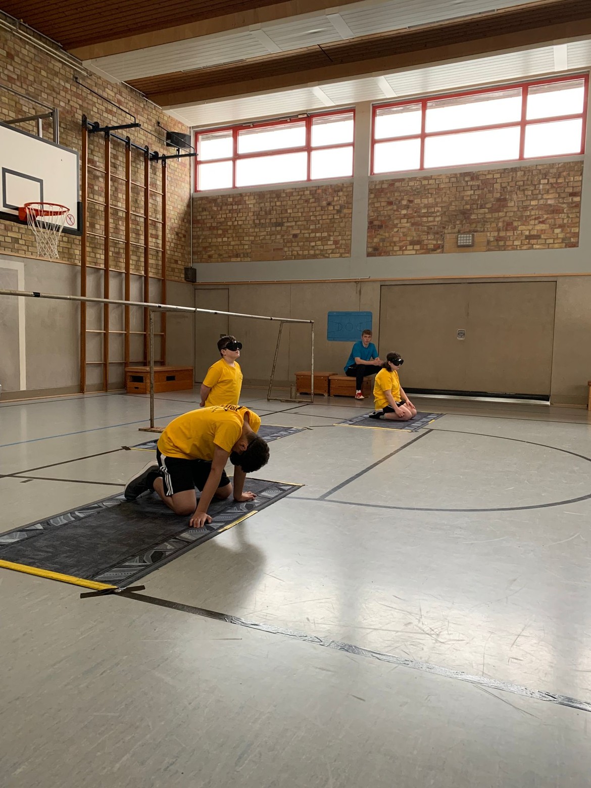 Drei Schüler mit gelben T-Shirts spielen Torball.